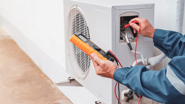 Air conditioner technician repairing central air conditioning system with outdoor tools