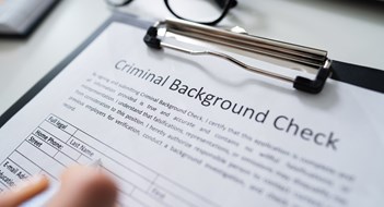 Close-up Of Human Hand Filling Criminal Background Check Application Form With Pen